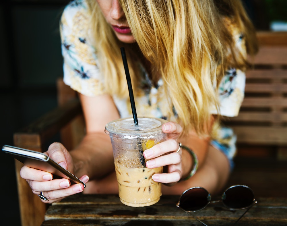 Woman drinking coffee using mobile phone