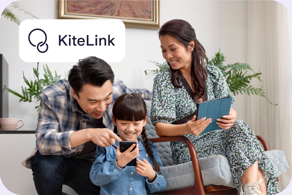 family photo with woman and man smiling down at a girl holding her phone