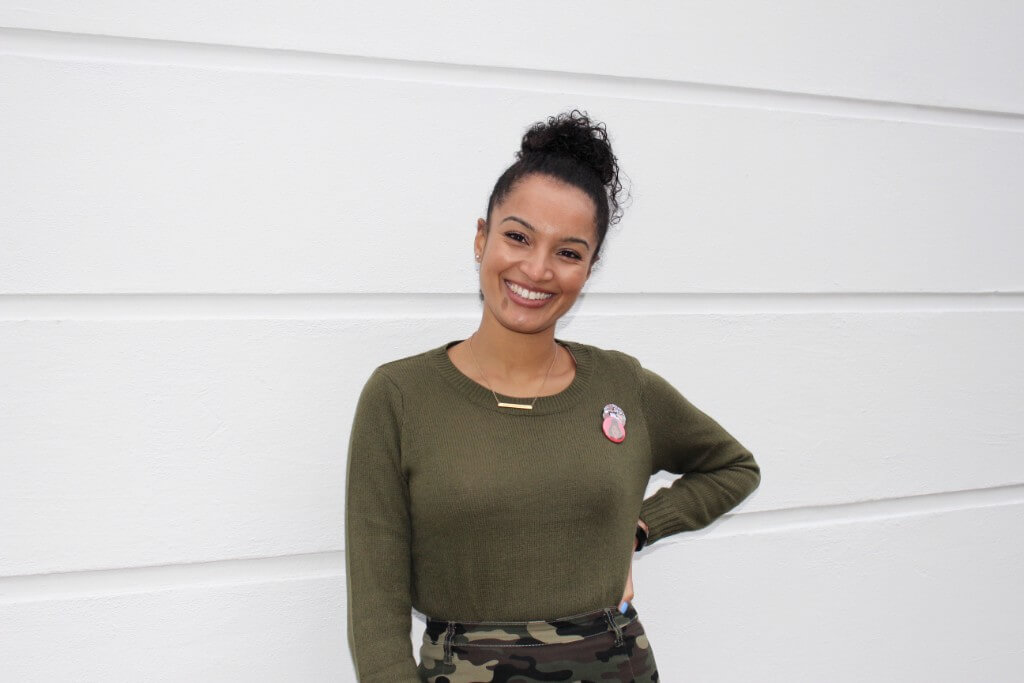 Khalia Ismain in a dark green top smiling and standing with her left hand on her hips