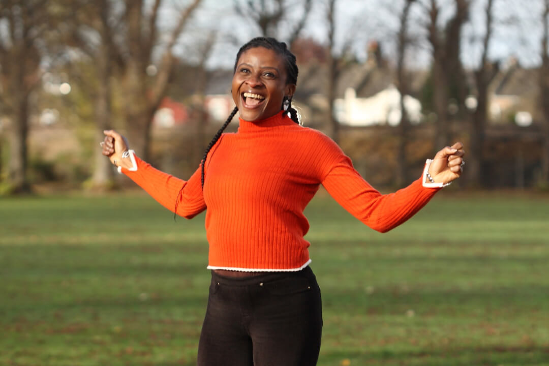 woman-in-orange-jumper-looking-happy