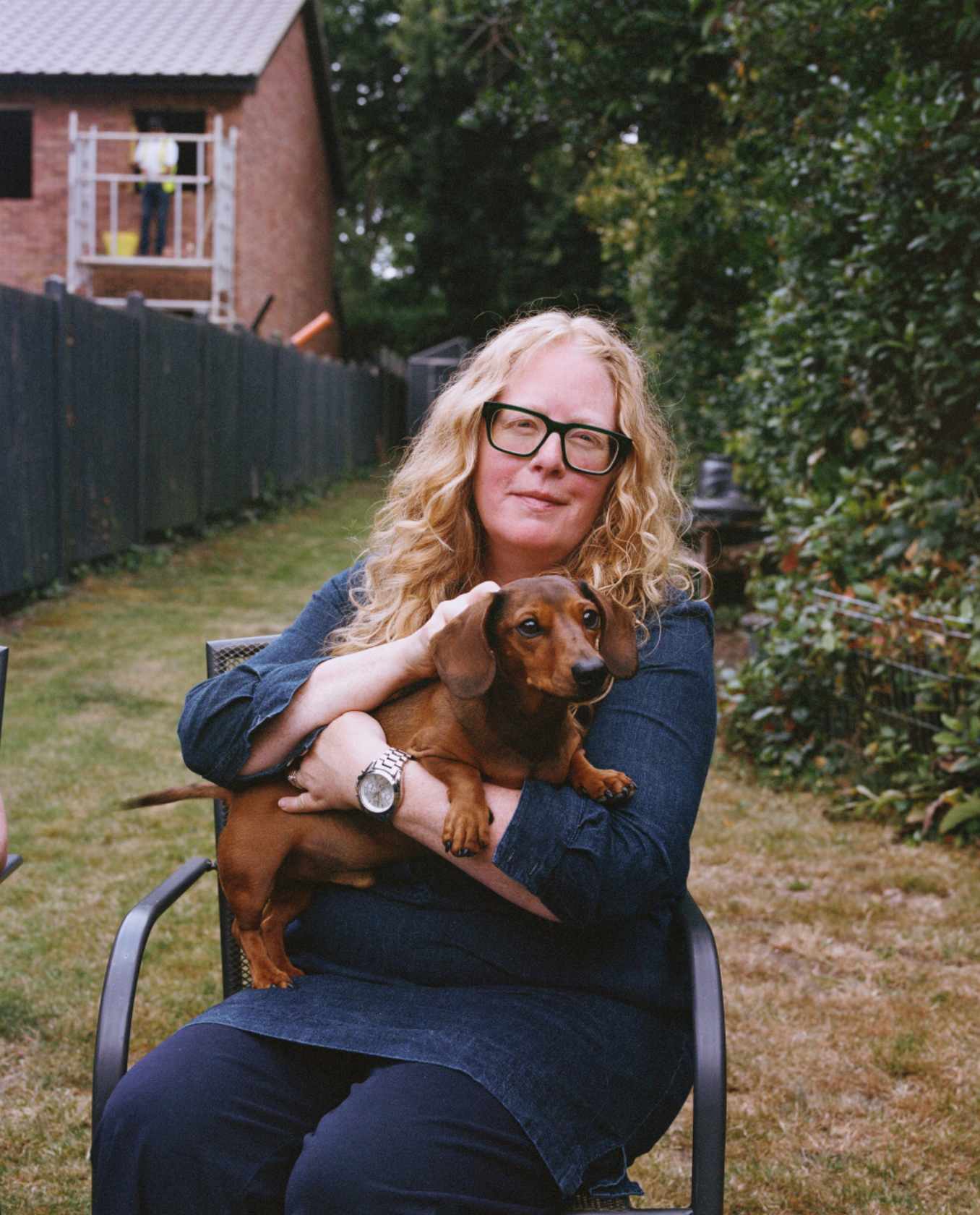 A woman sitting on the chair with daschund dog in garden