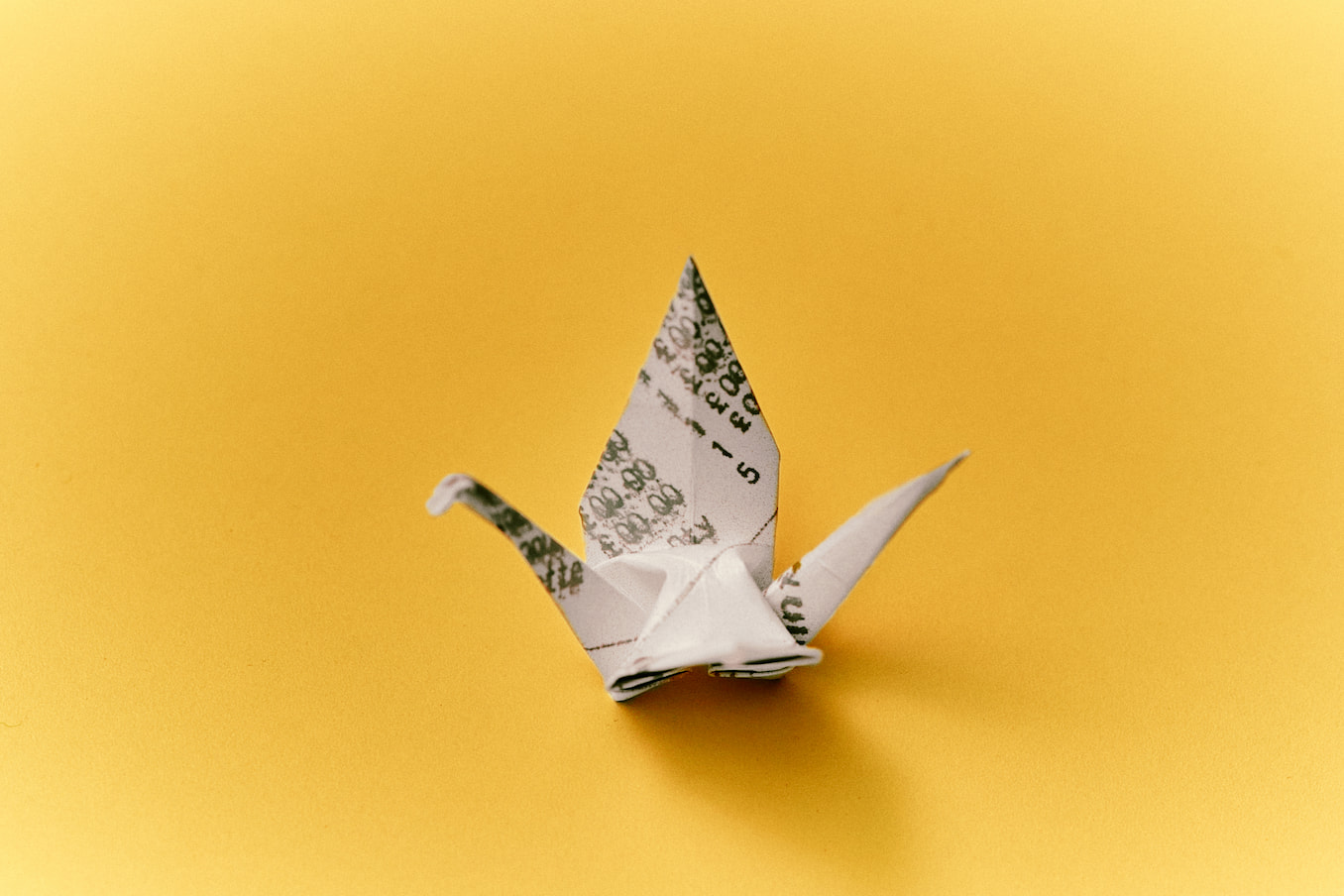 Origami bird made from a receipt with a yellow background