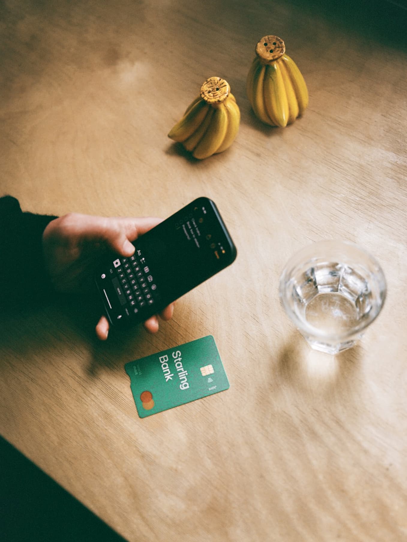 man-looking-at-phone-starling-joint-card-on-table