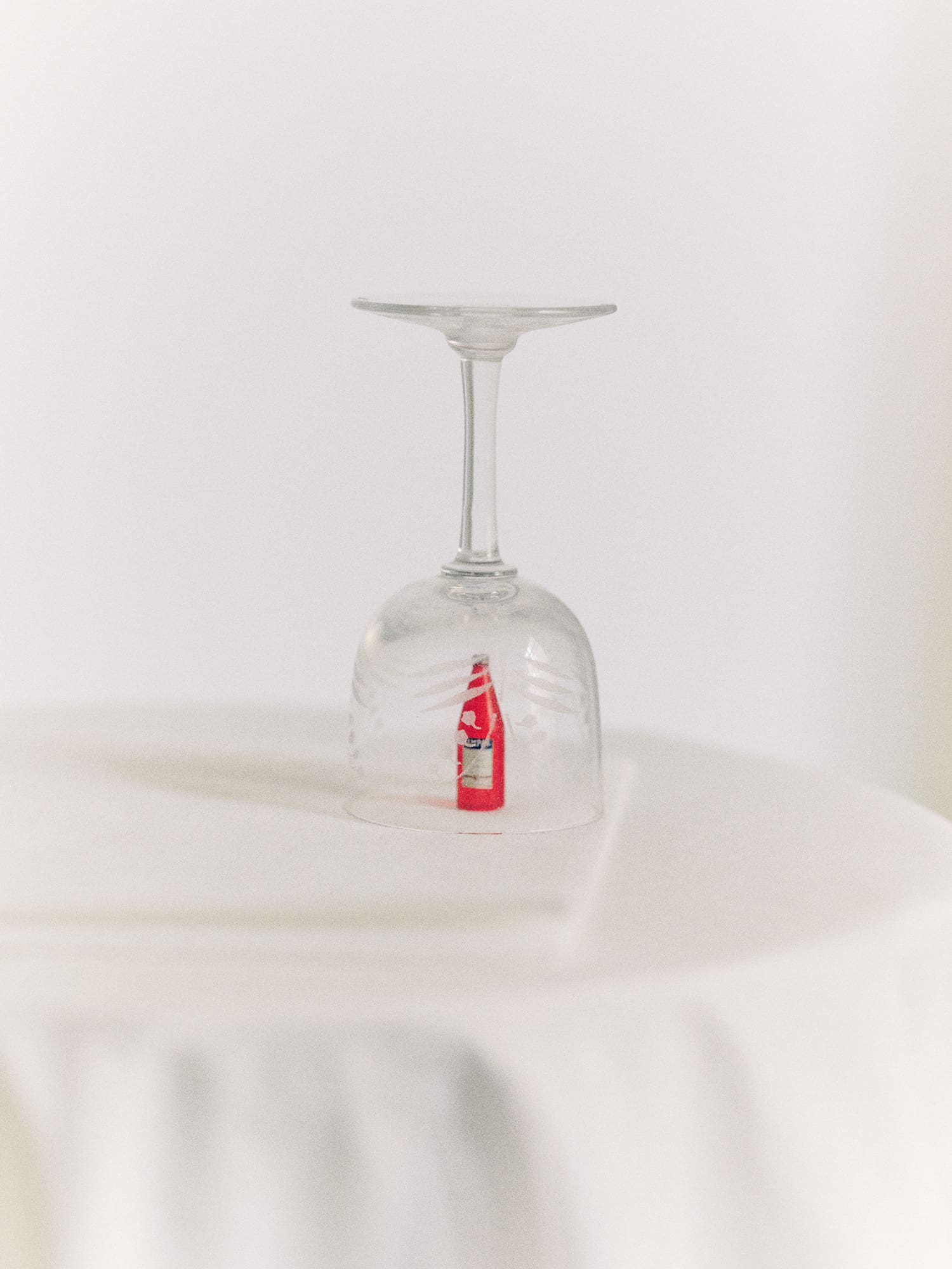 Miniature Campari bottle under upturned wine glass