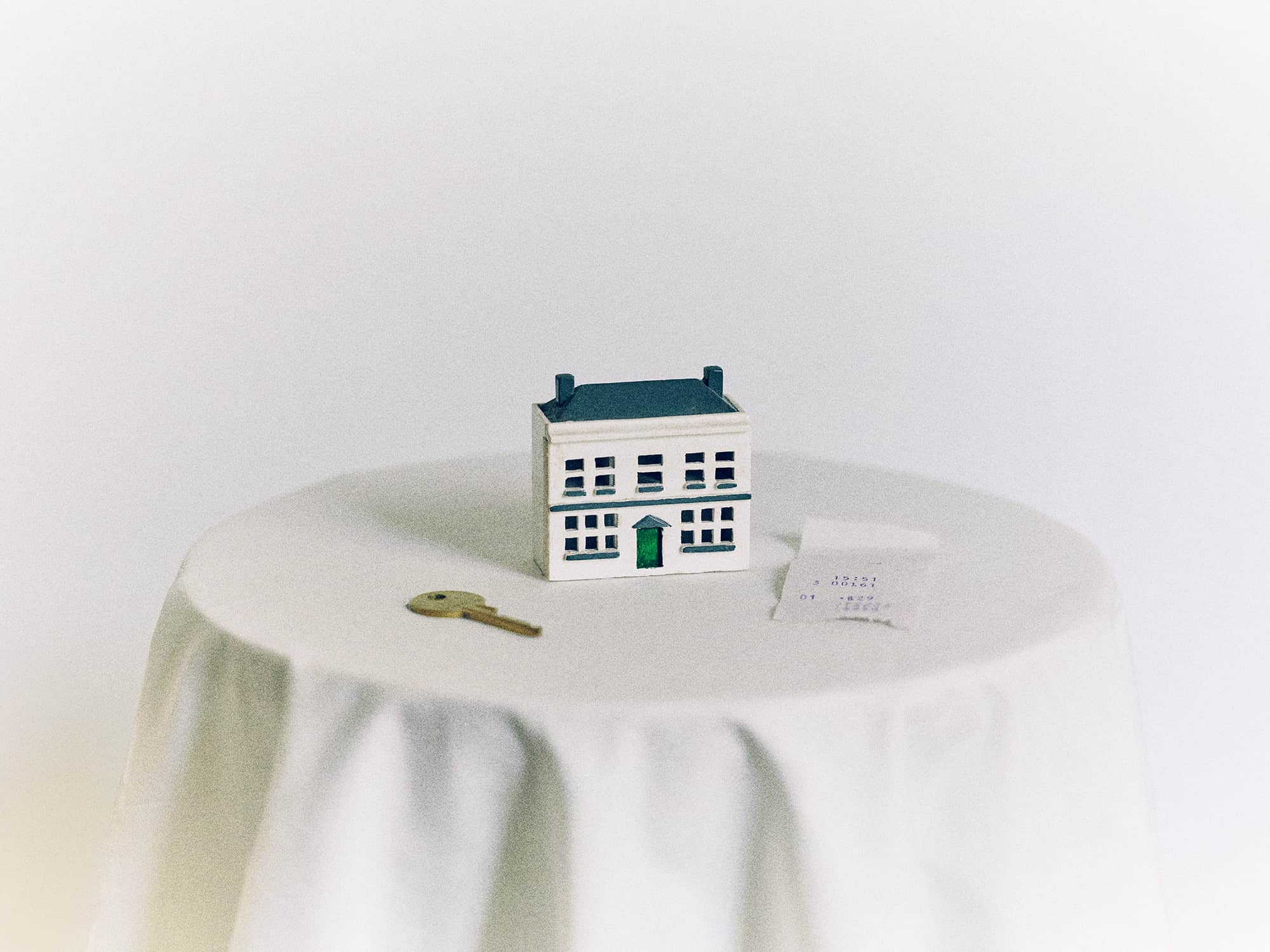 Miniature house with a key and a note on a table