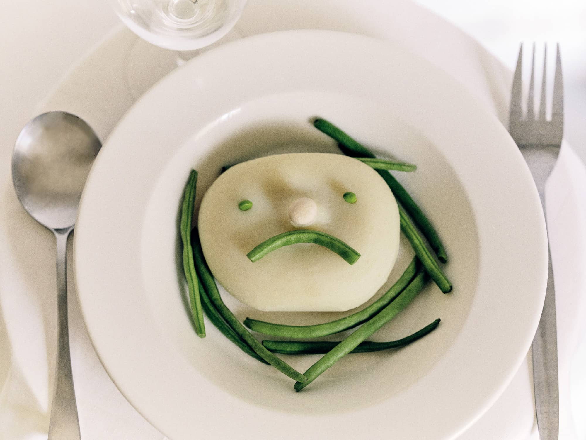 Green beans and mashed potato arranged to make a sad face