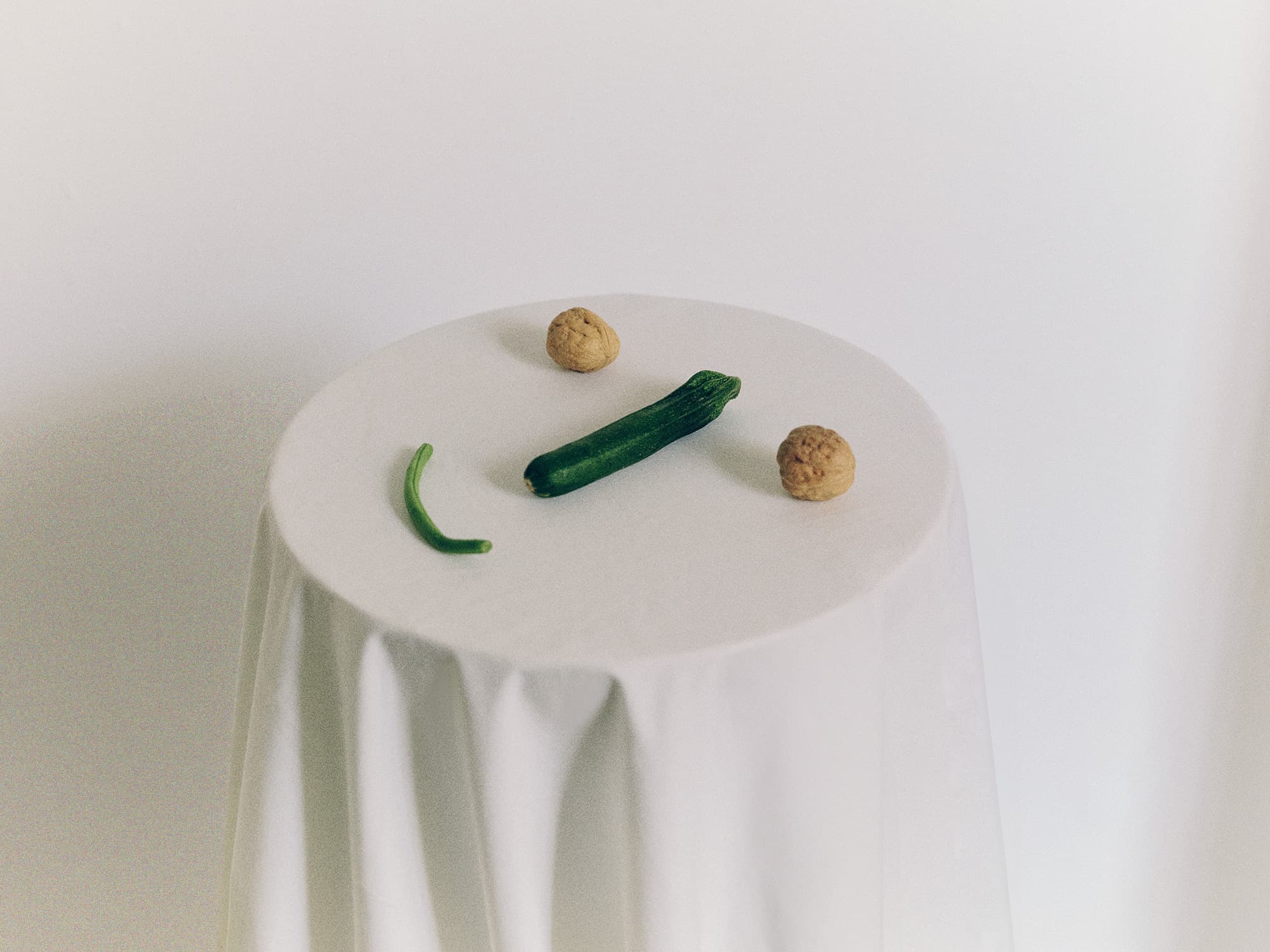 Two walnuts a courgette and a green bean arranged into a smiley face