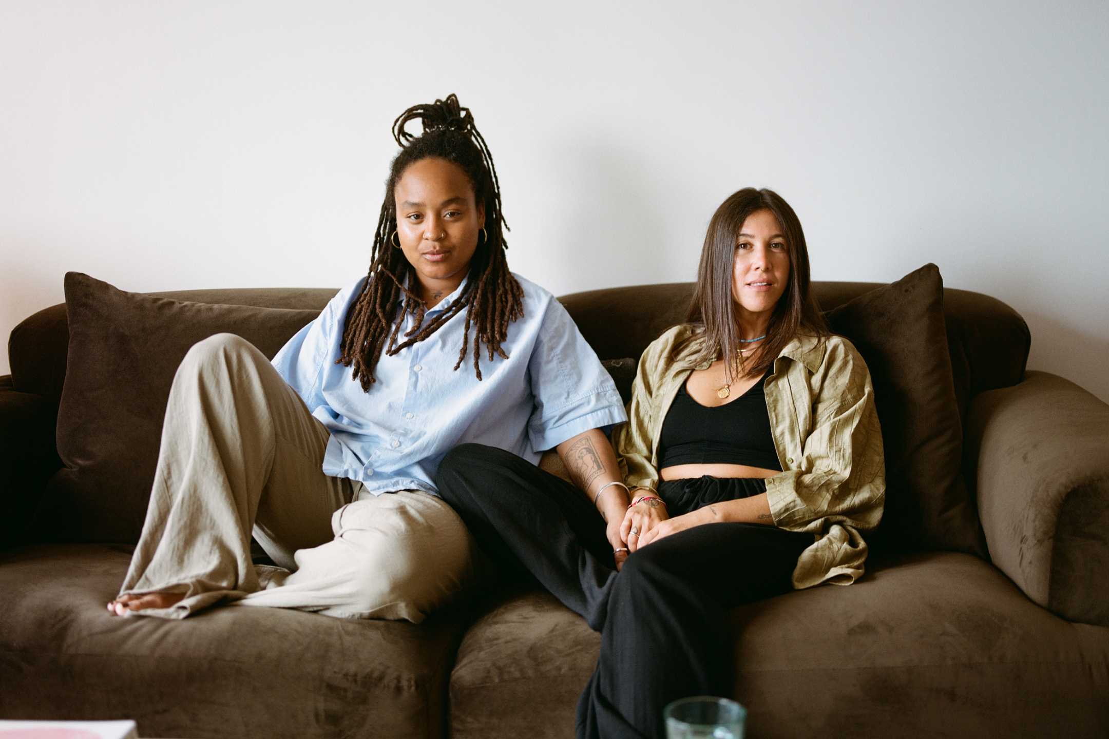 A couple sitting on the couch holding hands