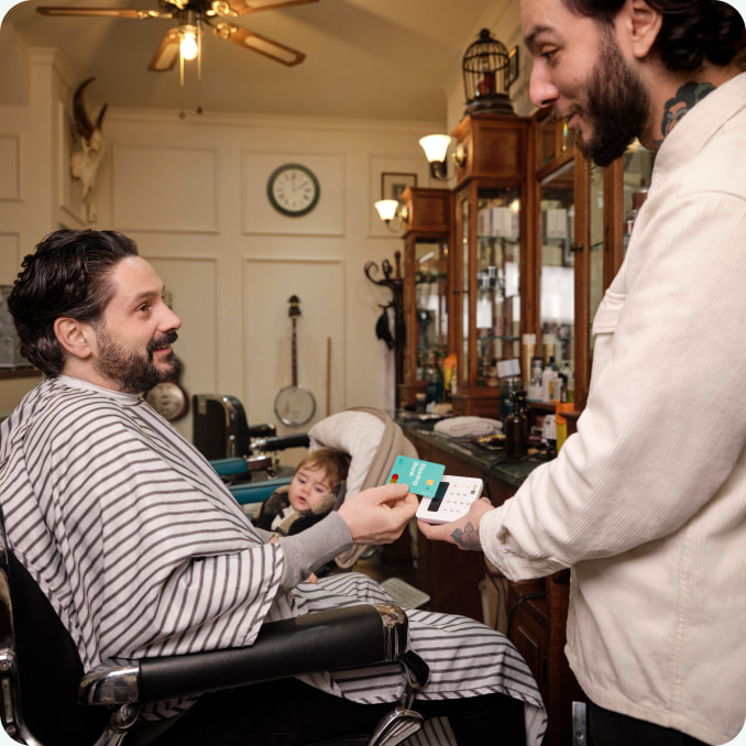 Man paying in a shop, holding out his Staring card to a payment terminal.