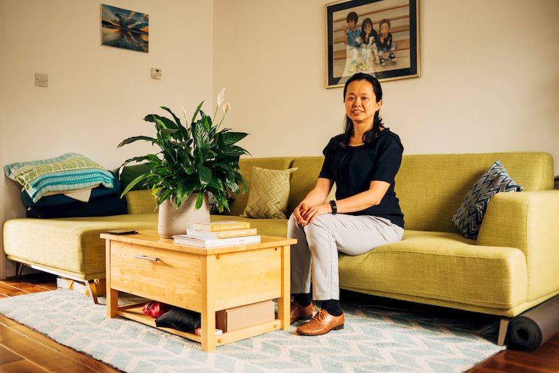 Christina Hsieh, founder of CH Simple Design sitting on a sofa smiling