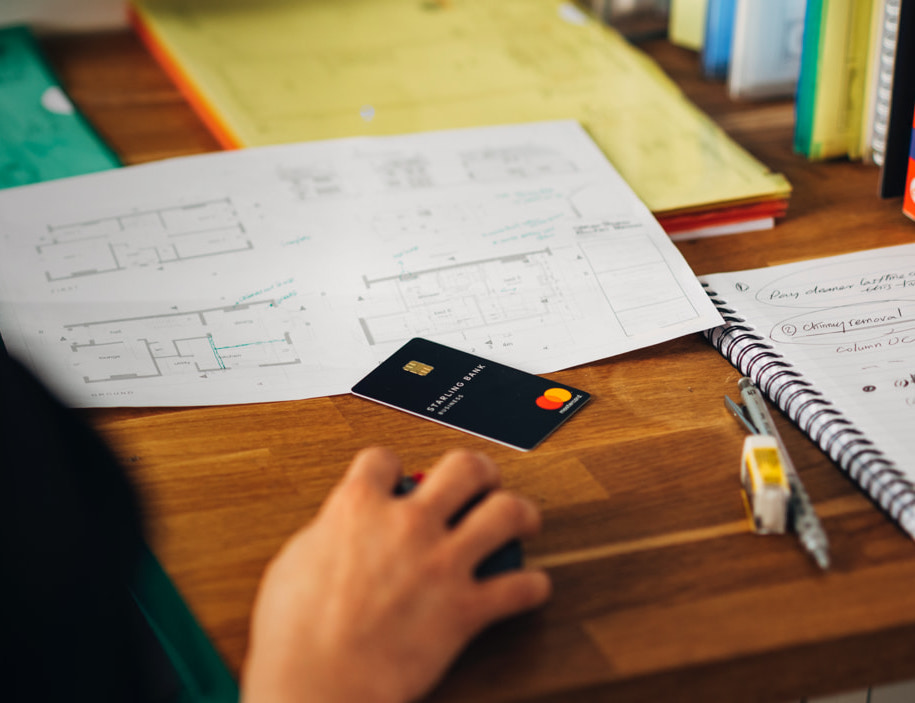 Business account card on table with floor plans scattered in the background
